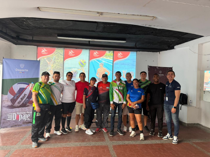Grupo de doce deportistas y funcionarios posando juntos en un evento institucional de antidopaje y deporte en Colombia.