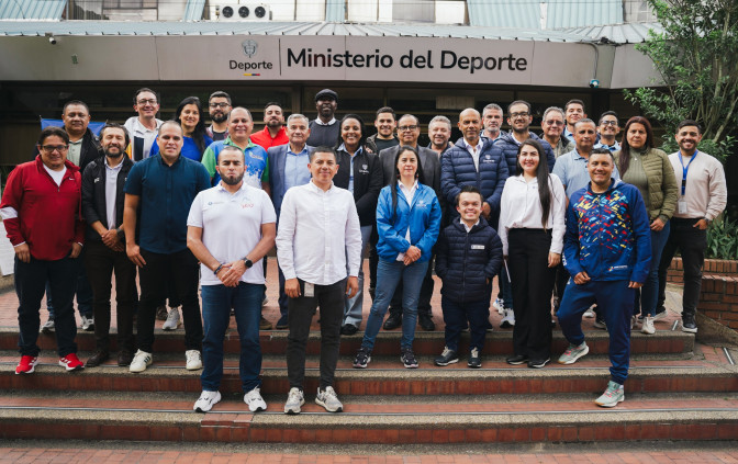 Grupo de aproximadamente 25 personas posando en las escaleras exteriores de la sede del Ministerio del Deporte de Colombia.