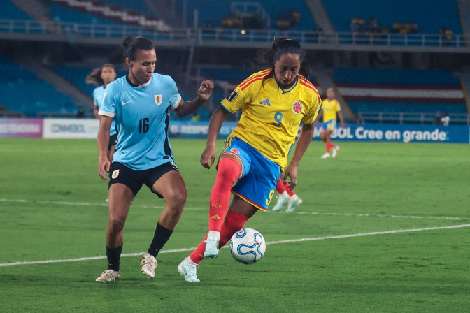 Jugadora número 9 de la Selección Colombia Femenina disputa el balón con la número 16 de Uruguay en partido nocturno.