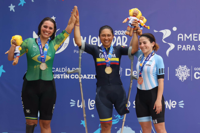 Tres ciclistas medallistas en podio de los Juegos Parapanamericanos: Colombia (oro), Brasil (plata) y Argentina (bronce), sonriendo con sus medallas.